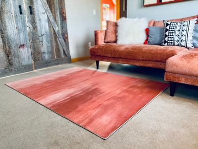Large pink yoga rug next to pink couch and wood barn doors