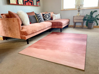 Large pink yoga rug next to pink couch and wood table in living room