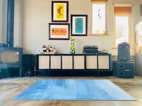 Blue yoga mat in front of end table and pictures on wall