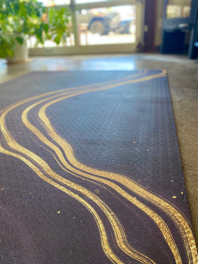 Black workout mat with wavy gold design in home