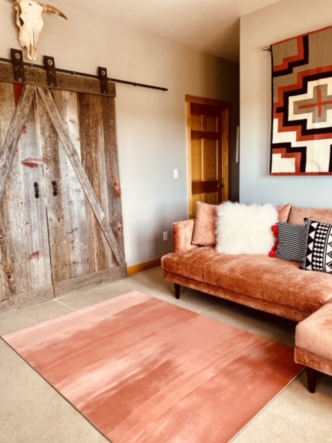 Large pink yoga rug next to pink couch and barn doors in living room