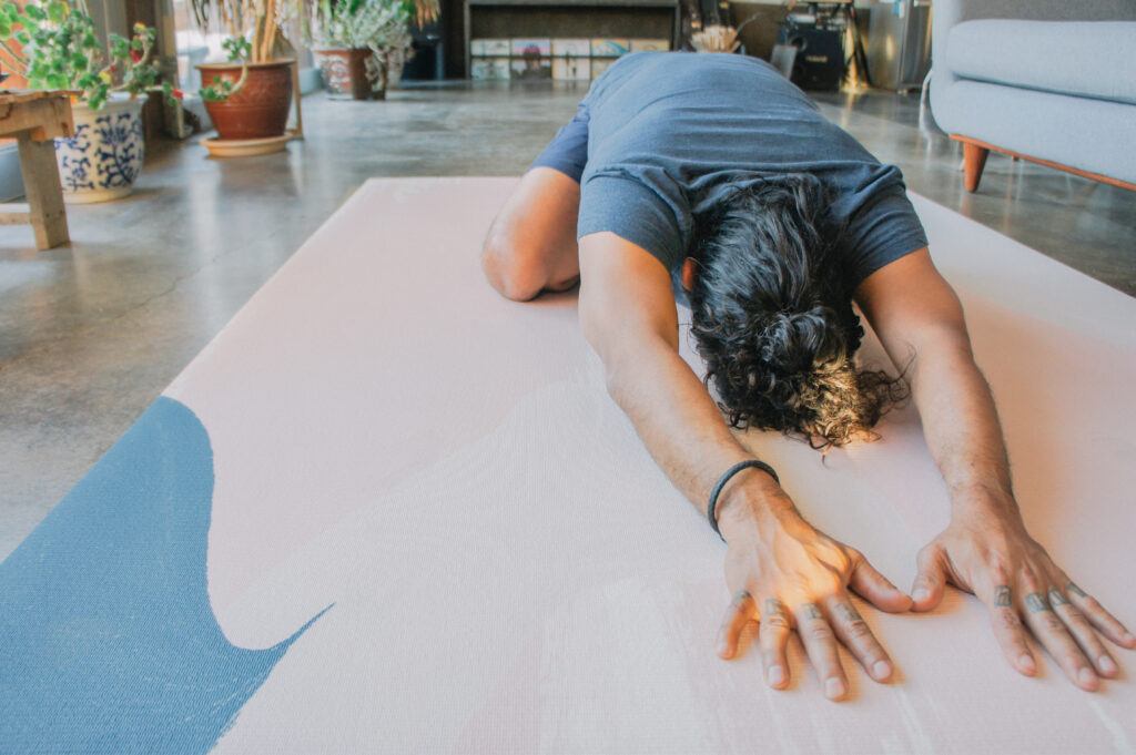 a man lie on the TADARugs yoga rug to perform yoga 